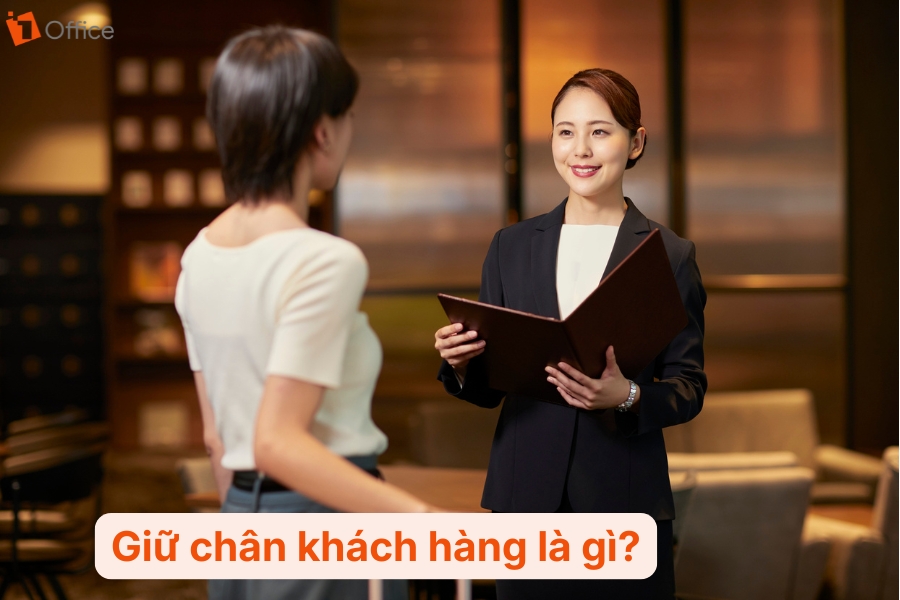 1 người bán hàng đang cầm sổ sách đang nói chuyện với 1 khách hàng nữ