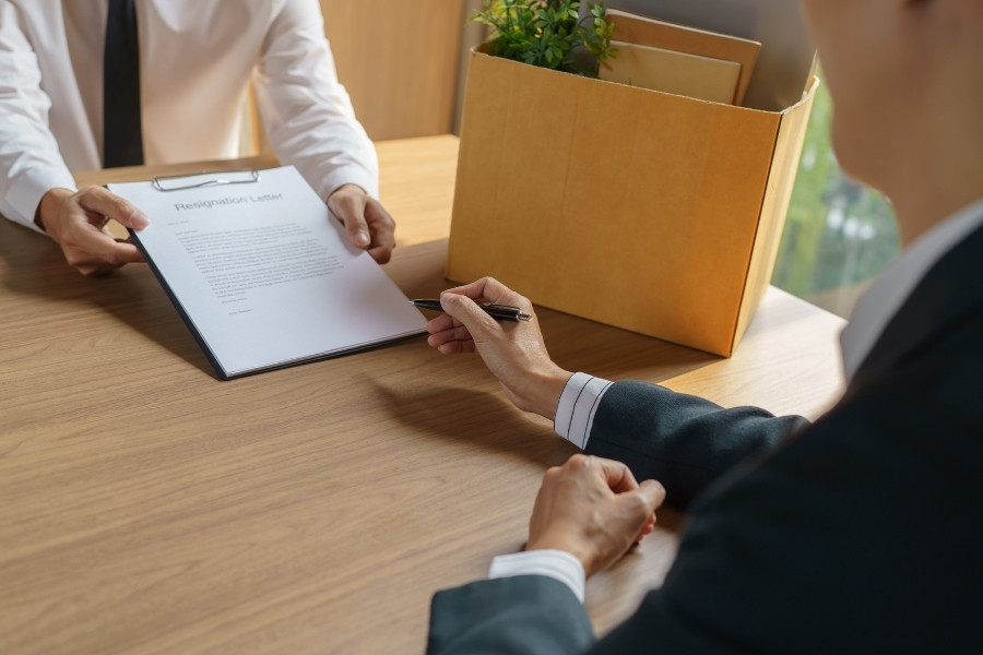 Hình ảnh nhân sự trao quyết định nghỉ việc cho người lao động trong buổi bàn giao công việc, minh họa quy trình xác nhận chữ ký và hoàn tất thủ tục trước khi chấm dứt hợp đồng lao động