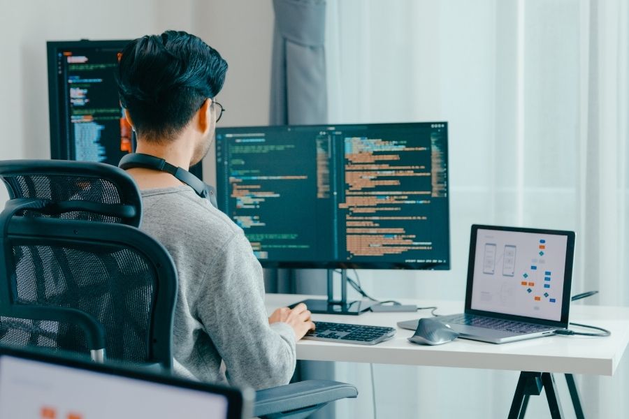Lập trình viên đang làm việc trên máy tính sử dụng các phần mềm AI hỗ trợ viết mã và tối ưu hóa mã nguồn.